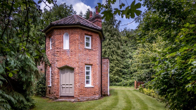 The two-storey octagonal tower for which Mustard Pot Cottage is named, surrounded by grass and trees, Norfolk